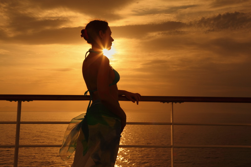 a woman leaning on a railing at sunset