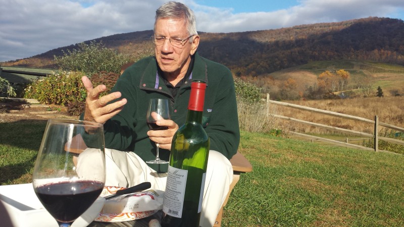 a man sitting at a table with wine bottles and a glass of wine