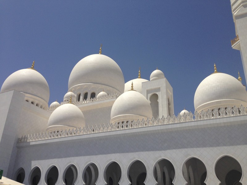 a white building with domes with Sheikh Zayed Mosque in the background