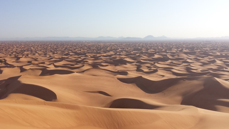 a sandy desert with mountains in the background