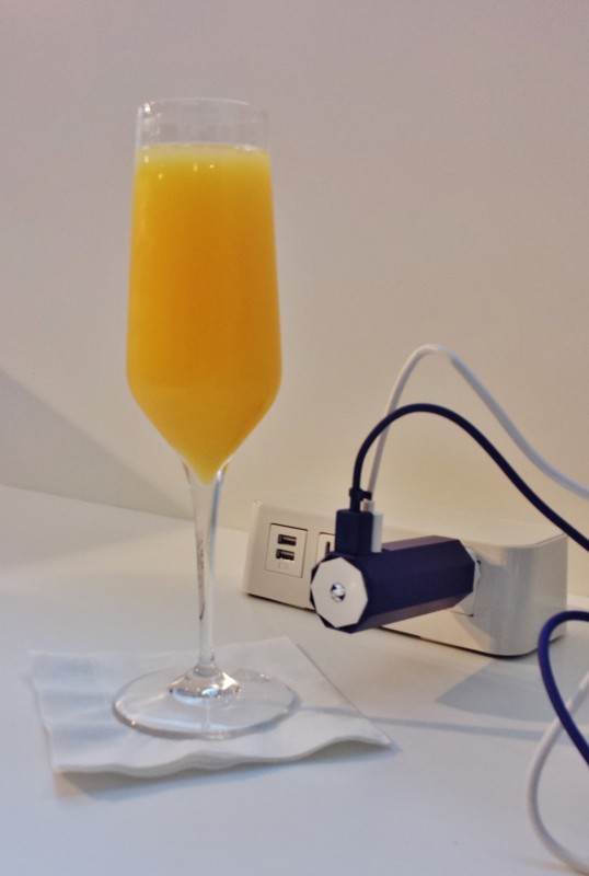 a glass of orange juice next to a power strip