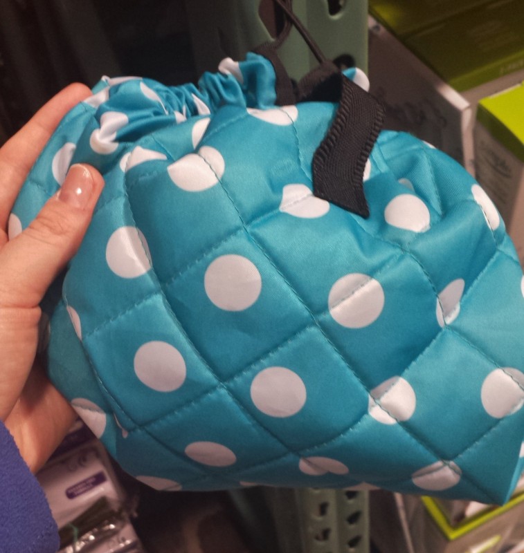 a hand holding a blue and white polka dot bag