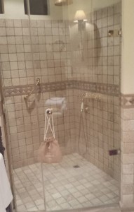 a glass shower with a bag on the wall