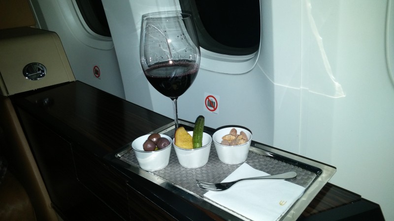 a glass of wine on a tray with food on it
