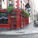 a red building with a gate with Temple Bar, Dublin in the background