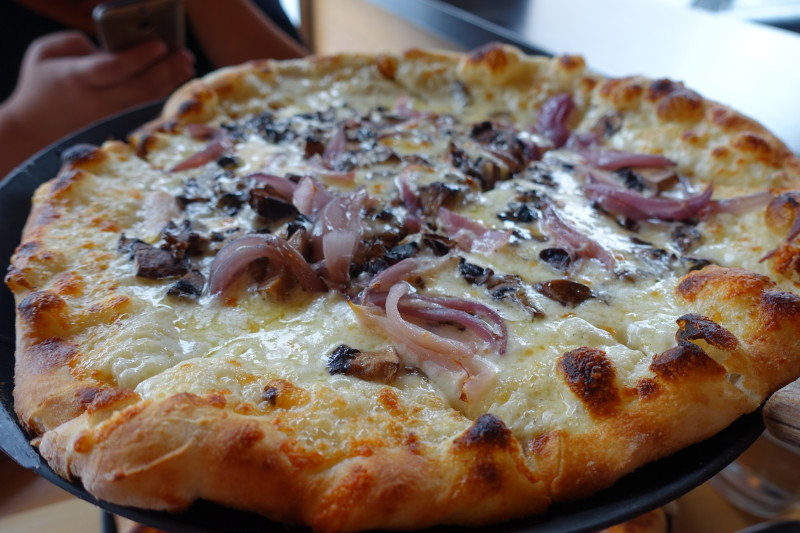 a pizza with onions and mushrooms on a plate