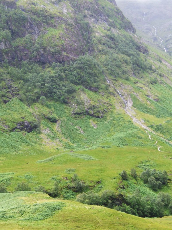 a green mountain with trees and a waterfall