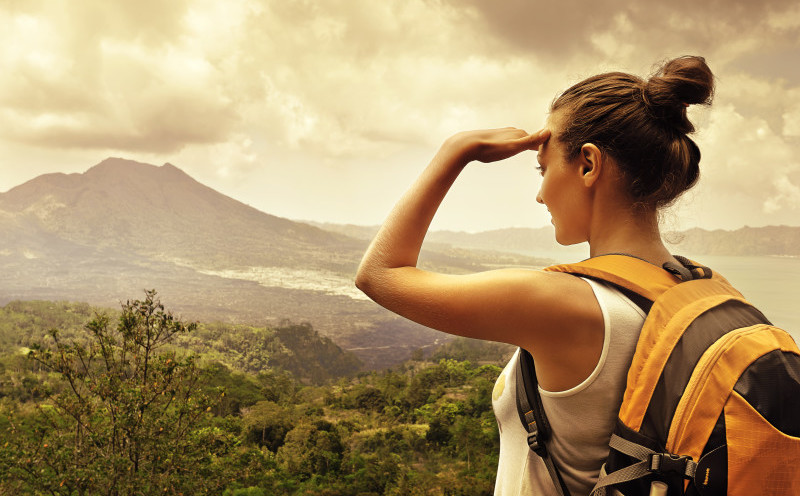 a woman with a backpack looking at a mountain range