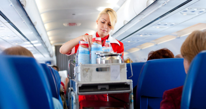 a woman in a red uniform putting drinks on a cart