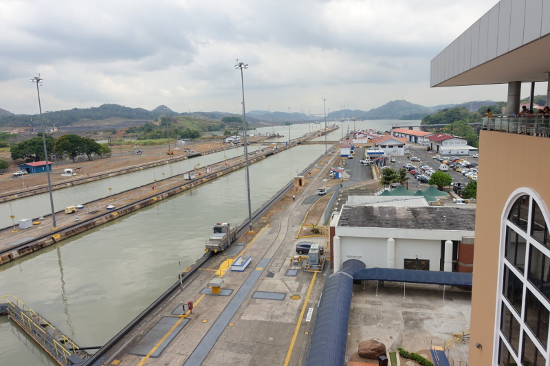 a canal with cars and buildings with Panama Canal in the background
