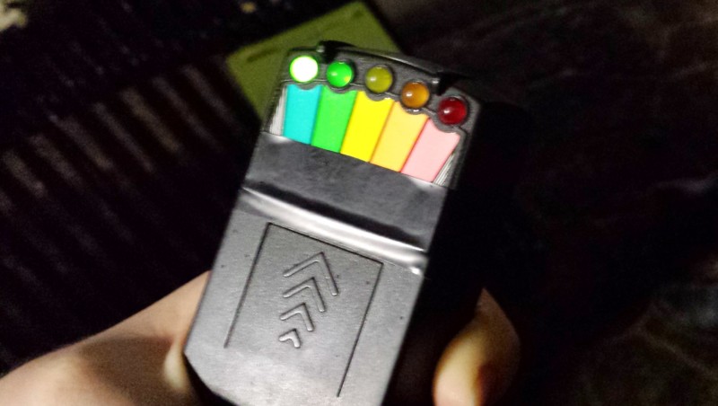 a hand holding a black device with multicolored lights