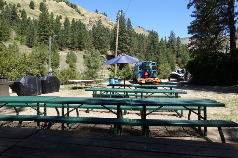 a picnic table with benches and a truck in the background