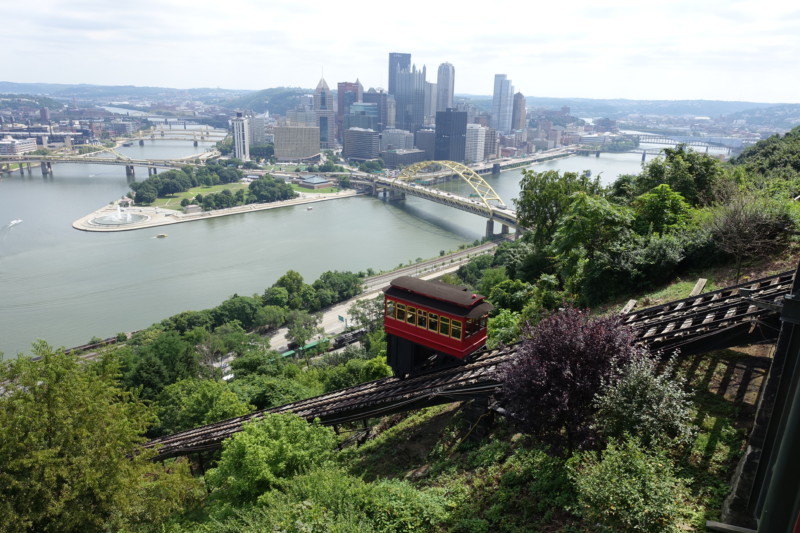 a train going down a hill with Duquesne Incline in the background