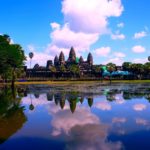 a body of water with trees and Angkor Wat in the background