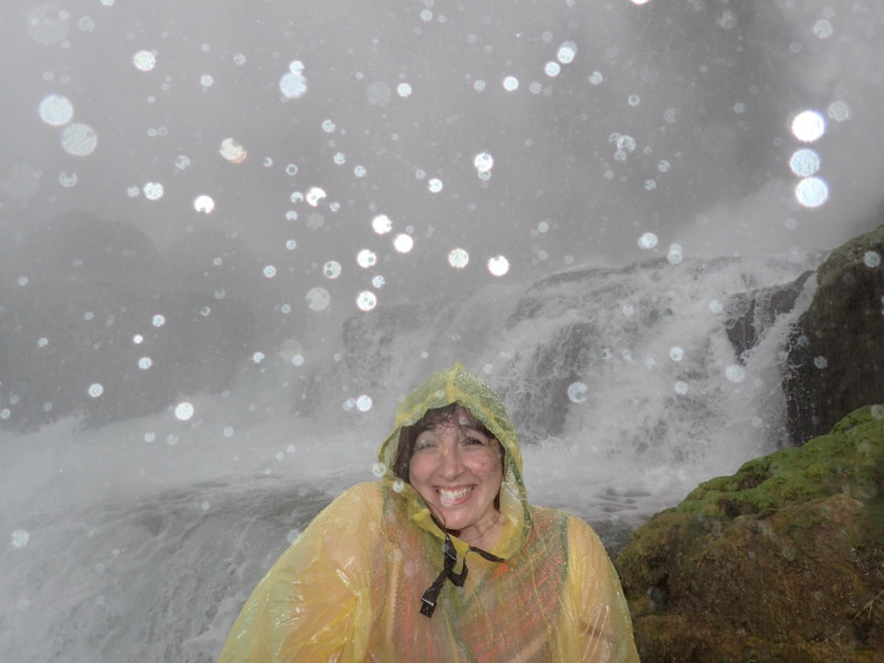 a woman in a raincoat in front of a waterfall