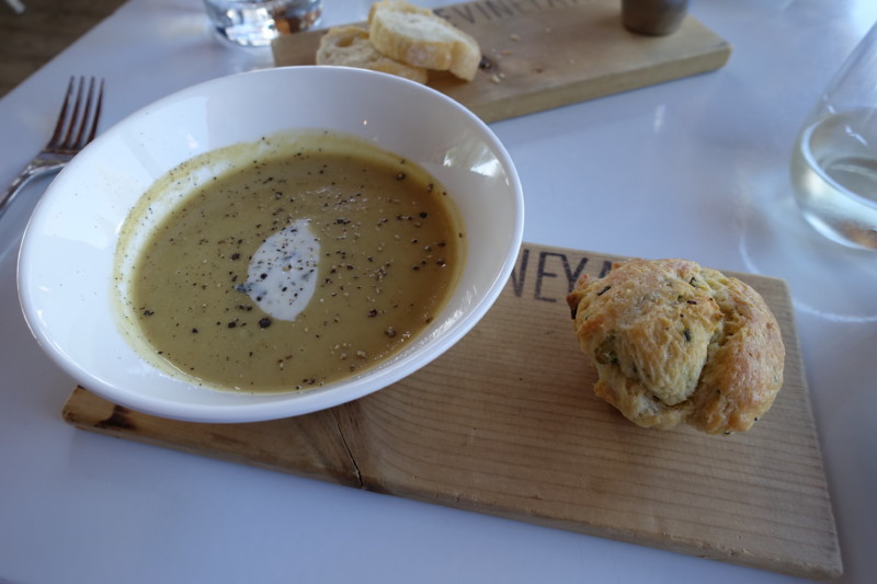 a bowl of soup and a pastry on a cutting board