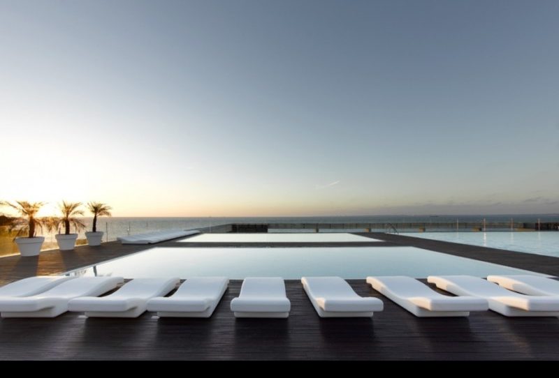 a pool with a deck and lounge chairs