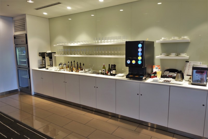 a white counter with a variety of wine glasses and a coffee machine