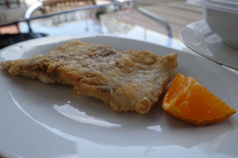 a piece of fried fish and an orange slice on a white plate