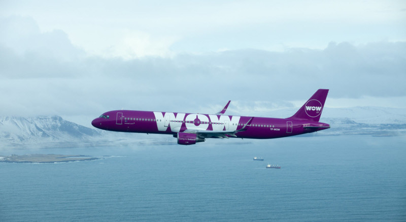 a purple airplane flying over water