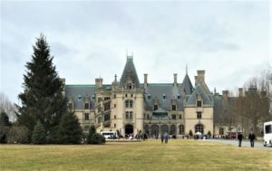 a large building with many people walking in front of it with Biltmore Estate in the background