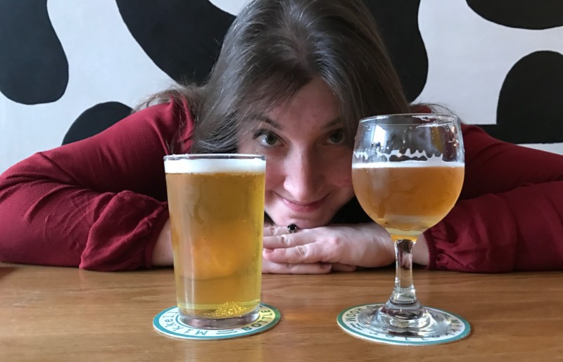 a woman leaning on a table with two glasses of beer