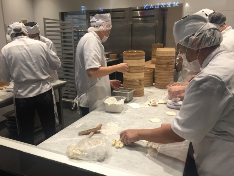a group of people in white uniforms preparing food