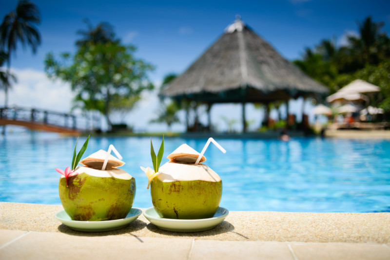two coconuts with straws on a pool side