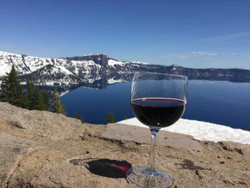 a glass of wine on a rock overlooking a lake