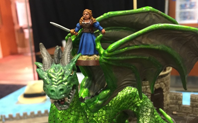 a toy figurine of a woman standing on a green dragon