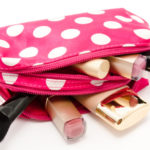 a pink cosmetic bag with makeup brushes and lipstick