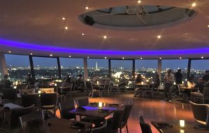 a room with tables and chairs and a view of the city from the top