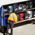 a man in a yellow vest looking at luggage on a trailer