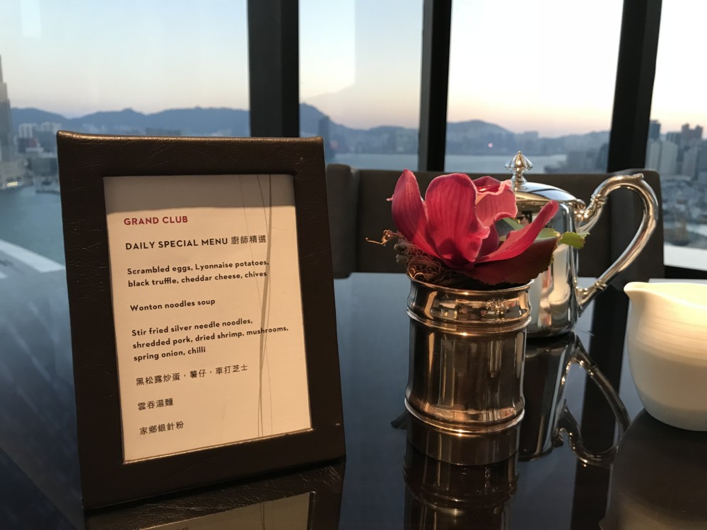 a menu frame and a flower in a metal container on a table
