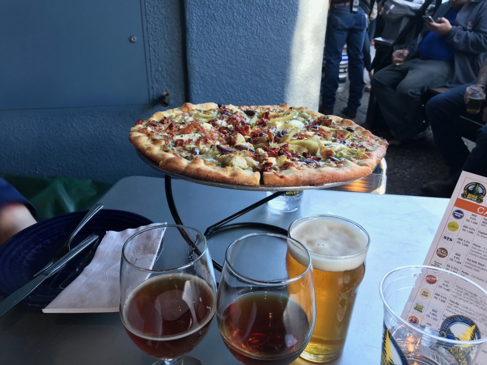 a pizza on a table with glasses of beer