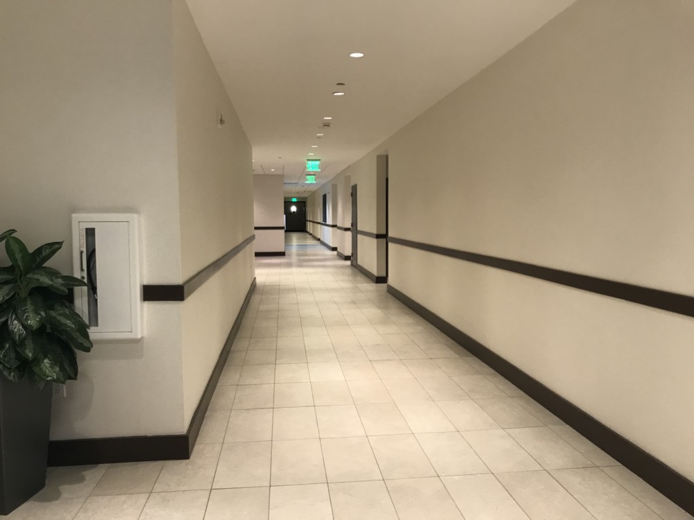 a hallway with white walls and a green light